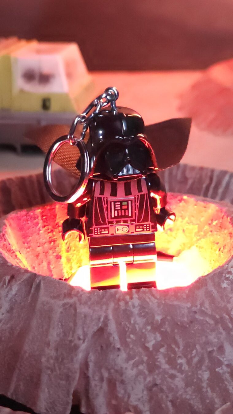 Glowing Santoki LEGO Darth Vader Keychain Light Santoki LEGO Darth Vader Keychain Light glowing red from below inside a sci-fi crater display