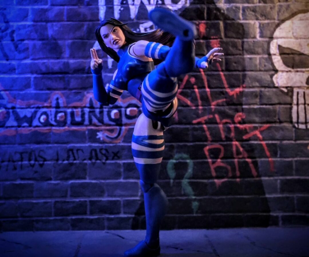 Psylocke High Kick Marvel Legends Urban Diorama Photography Psylocke Marvel Legends action figure delivering a high kick in front of urban graffiti wall with dramatic lighting