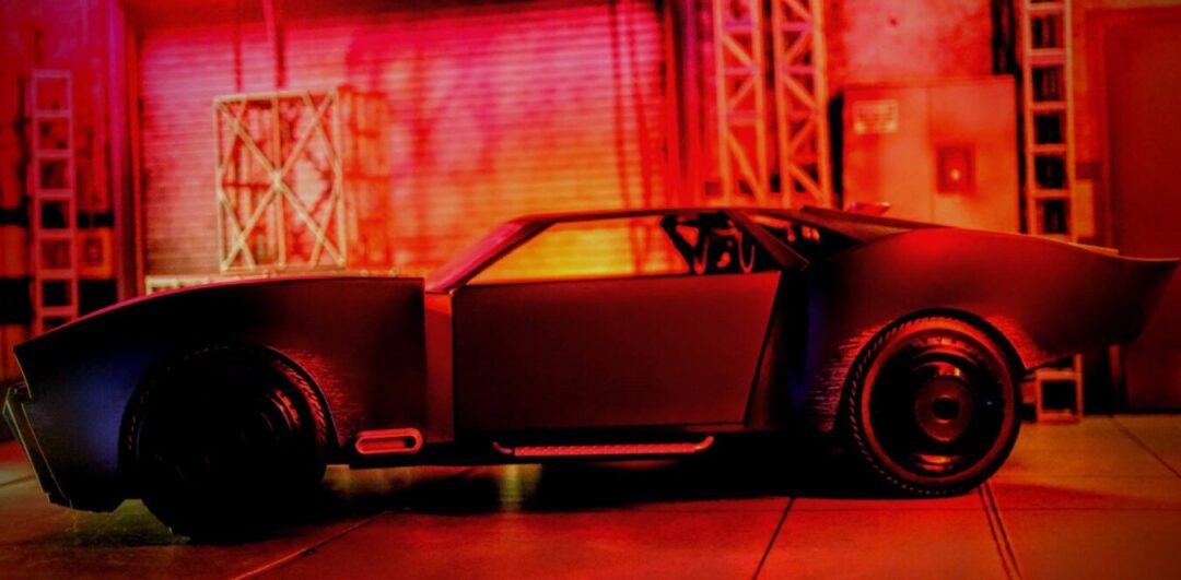 Side view of McFarlane Toys The Batman Batmobile DC Multiverse Gold Label vehicle under red lighting
